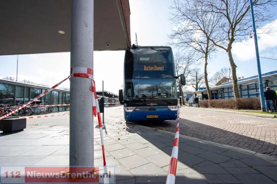 Dubbeldekker Qbuzz vast onder uitstekende hoek gebouw in Emmen