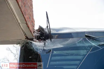 Dubbeldekker Qbuzz vast onder uitstekende hoek gebouw in Emmen — foto 2 van 3