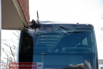 Dubbeldekker Qbuzz vast onder uitstekende hoek gebouw in Emmen — foto 3 van 3