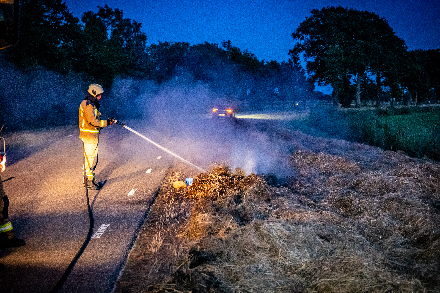 Brandweer blust broei in stro langs weg in Nijeveen — foto 1 van 4