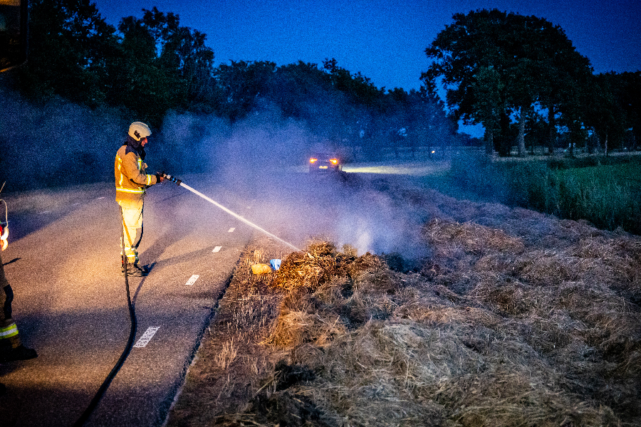 Brandweer blust broei in stro langs weg in Nijeveen