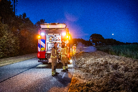 Brandweer blust broei in stro langs weg in Nijeveen — foto 4 van 4