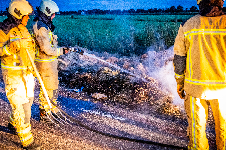 Brandweer blust broei in stro langs weg in Nijeveen — foto 3 van 4